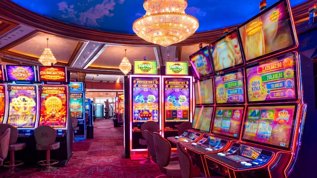 Sala de slots de Casino Arena Maipú con arañas y sillas con el logo M