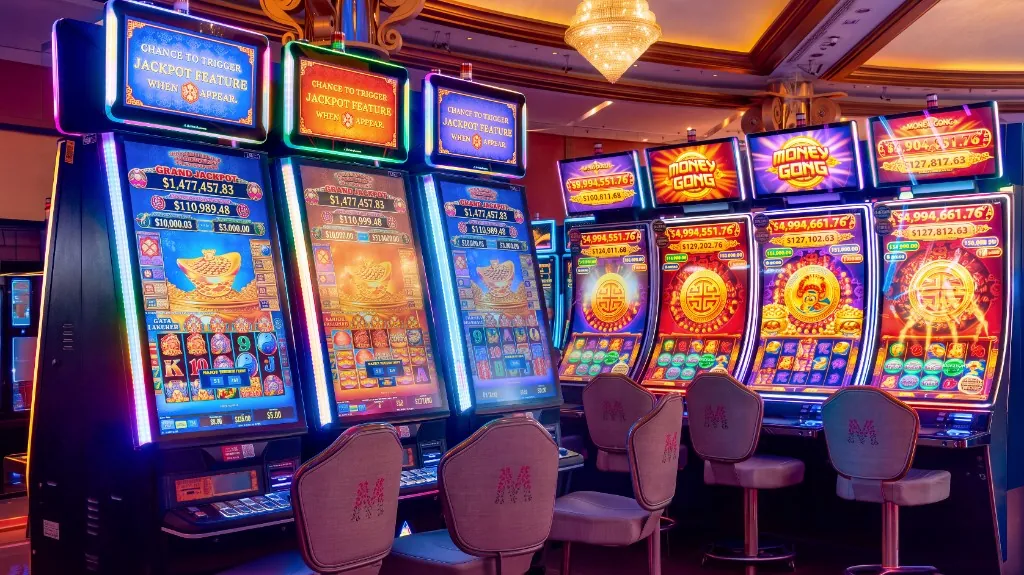 Máquinas de jackpot con sillas con el logo M en Casino Arena Maipú