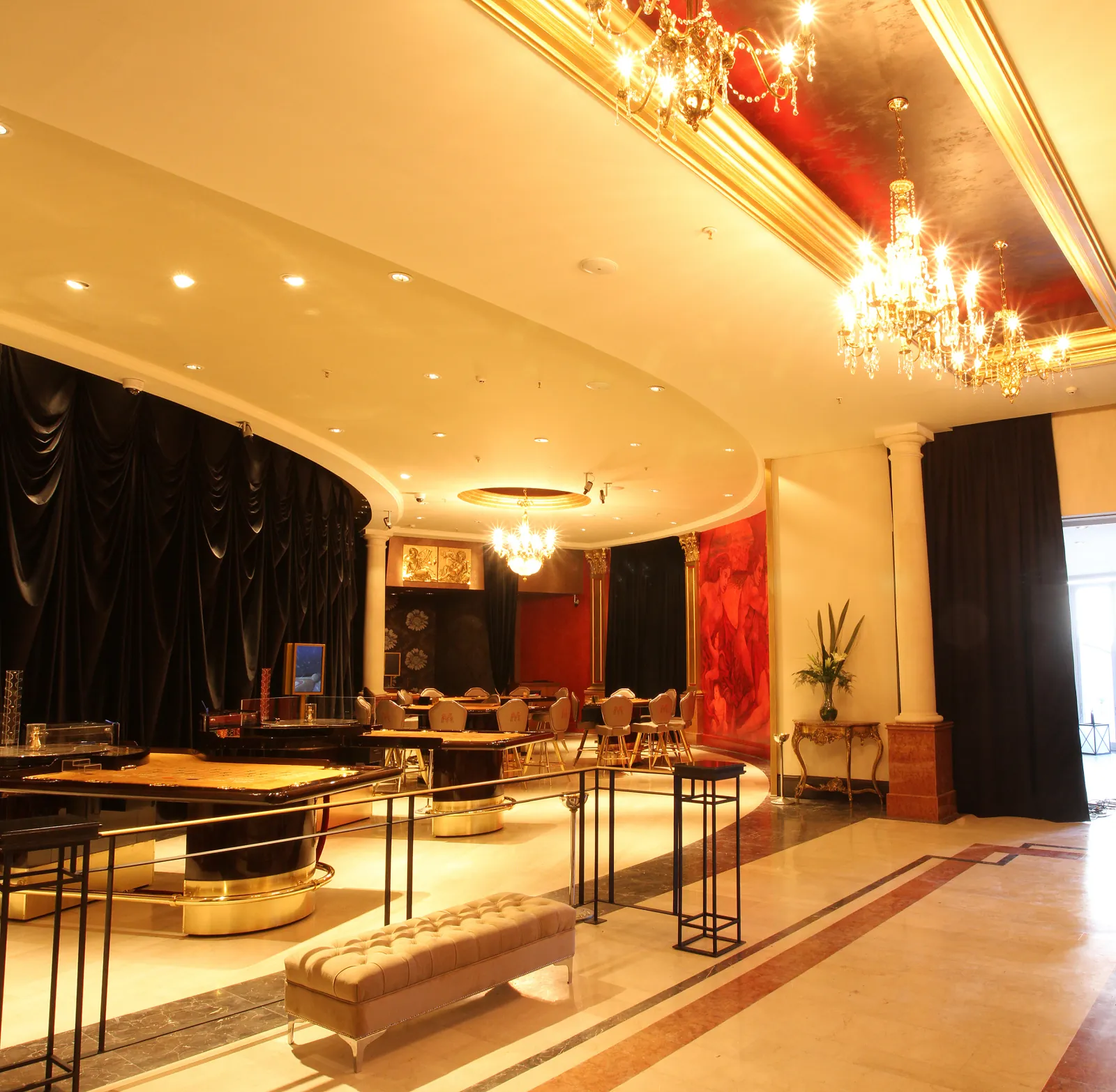 Sala VIP de Arena Maipú, con mesas, arañas de cristal y el mural